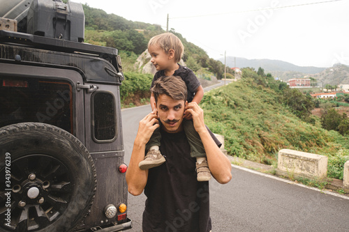 A man carries a child on his should in the countryside