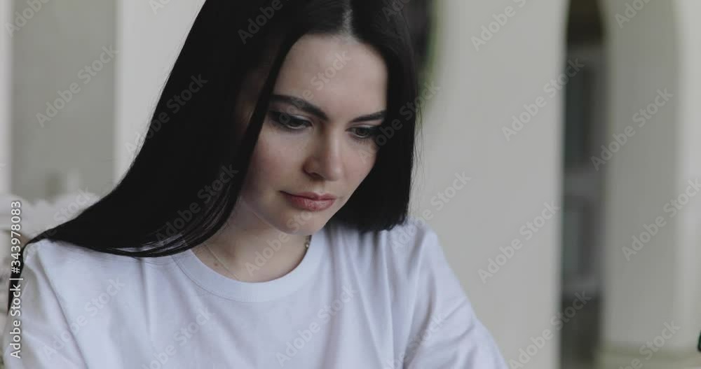 Portrait of serious lady working with laptop at table in light home Portrait of serious lady working with laptop at table in light home