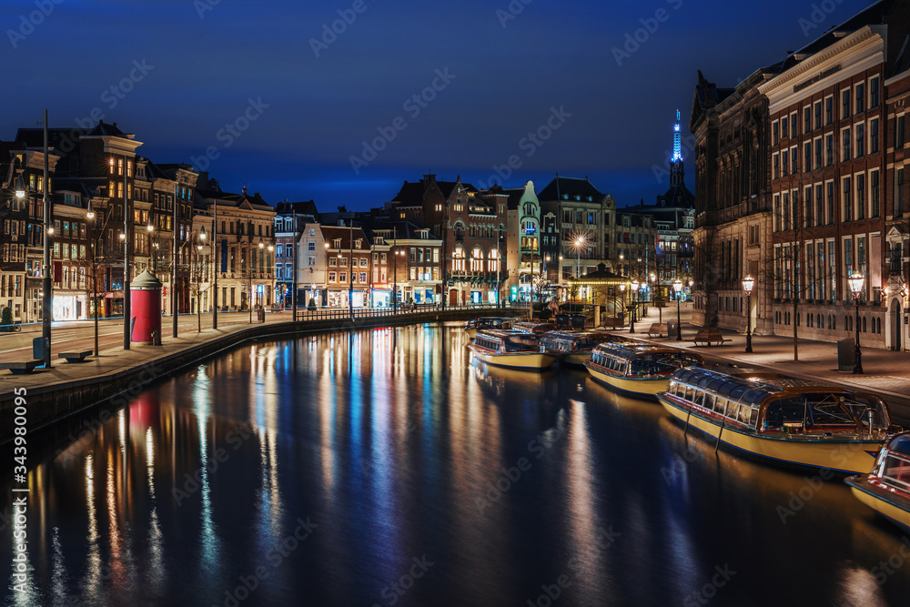 Amsterdam canal, Amstel river with city illumination reflection, Netherlands, Dutch city at night.