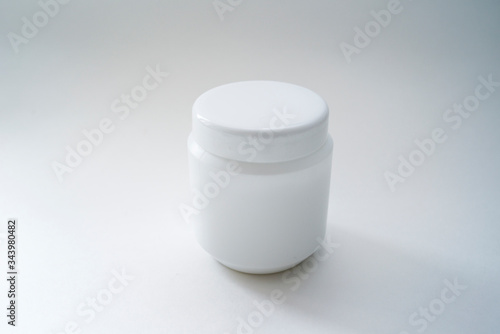 Jars of care products in white in various shapes and with different lids on a light background