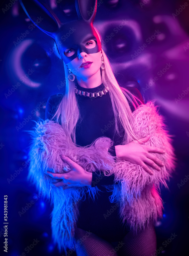 sexy girl in a bodysuit and fur coat with a rabbit mask in the neon light sexy girl in a bodysuit and fur coat with a rabbit mask in the neon light