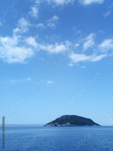 Small island in the middle off the sea ocean with bright blue sky and small clouds. Vertical image of a landscape. © Studio f20