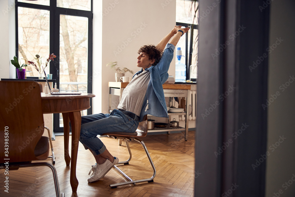 Handsome guy stretching hands while working on laptop Handsome guy stretching hands while working on laptop