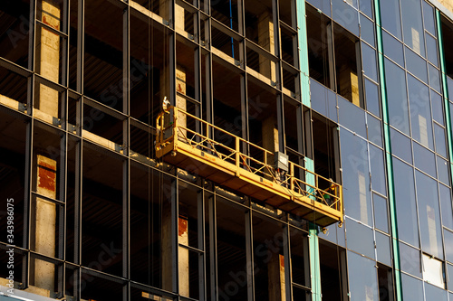 Photos Suspended construction craddle near wall of hightower building with insulation and ventilated facade on construction site