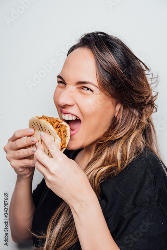 Portrait of girl eating an arepa of shredded meat. Typical Latin American food