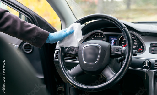 Hands in protective gloves clean the wheel of a car with a napkin