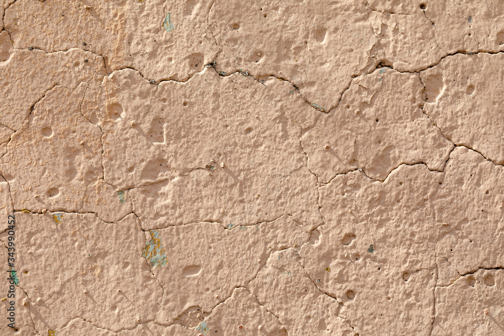 The texture of the concrete wall with irregularities, cracks, painted in sand color. Abstract background.