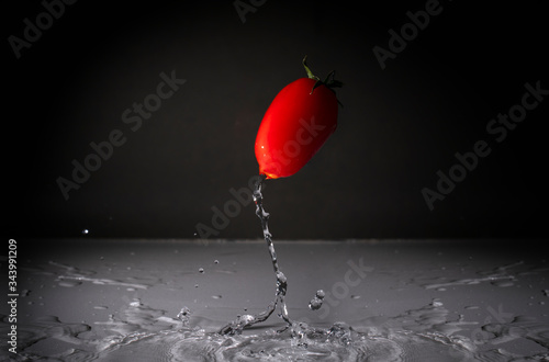 a jumping red tomato and water drops