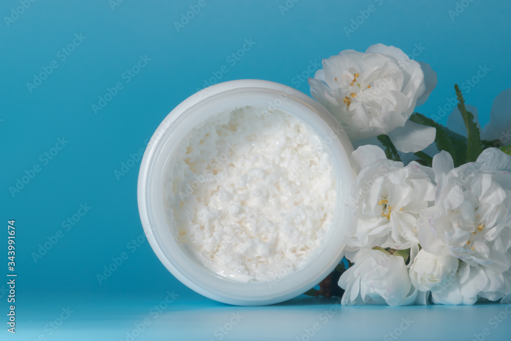 Facial oxygenating detox cream texture. Face cream with herbal cherry flowers on blue background. Organic cosmetics with oxygen bubbles Facial oxygenating detox cream texture. Face cream with herbal cherry flowers on blue background. Organic cosmetics with oxygen bubbles