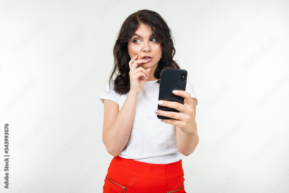 a girl with black hair sits on the Internet in social networks holding a phone in her hand and looking thoughtfully to the side a girl with black hair sits on the Internet in social networks holding a phone in her hand and looking thoughtfully to the side
