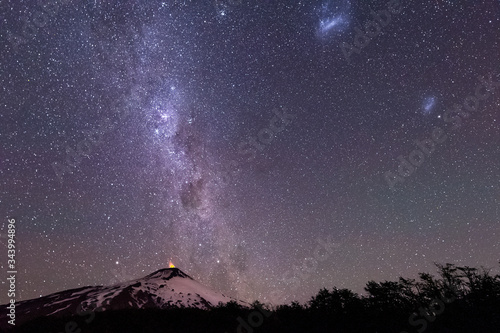 Thousands of stars in the sky with the Milky Way above the Villarrica Volcano in Chile with silhouettes of some trees