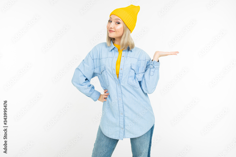 stylish blonde girl in a casual look with a hat with a holding hand with a template on a white background stylish blonde girl in a casual look with a hat with a holding hand with a template on a white background