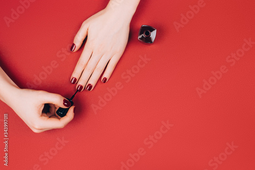 Woman making manicure by herself on marsala background. photo