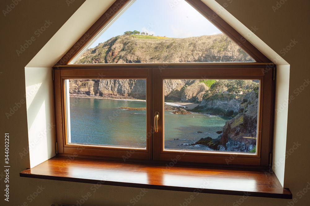Fototapeta premium Closed window and beautiful picture outside, nature view, resort and resting. Sunny summers or spring day with green grass, sea or ocean, bright and vibrant colors. Tourism, hotels or home mood.
