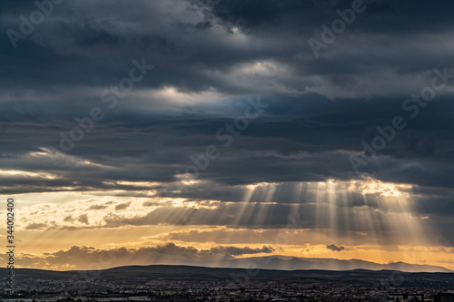 Obraz na płótnie Panoramic view of dramatic sun ray through low clouds over city at sunset. The sun cuts through the clouds over the city. Sunbeams on the city w salonie