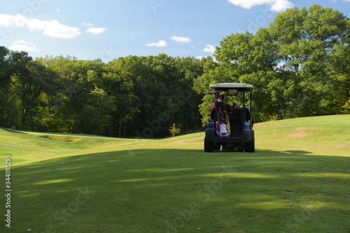 a golf cart drives across a beautiful green fairway on a sunny afternoon