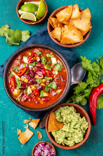 Mexican food concept background with chile black bean soup, guacamole and nachos totopos. Top view