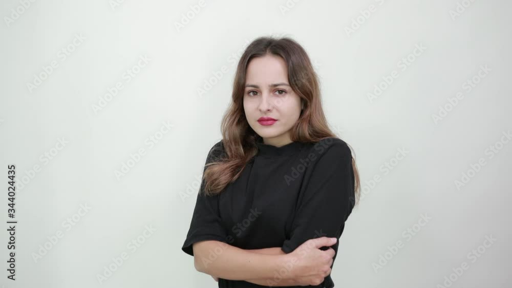 Cute young brunette woman in black t-shirt, blue jeans with belt on gray background, disappointed girl with a bad mood crossed her arms Cute young brunette woman in black t-shirt, blue jeans with belt on gray background, disappointed girl with a bad mood crossed her arms