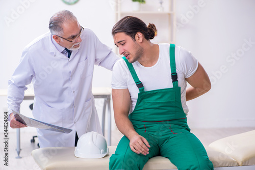 Young male contractor visiting old doctor