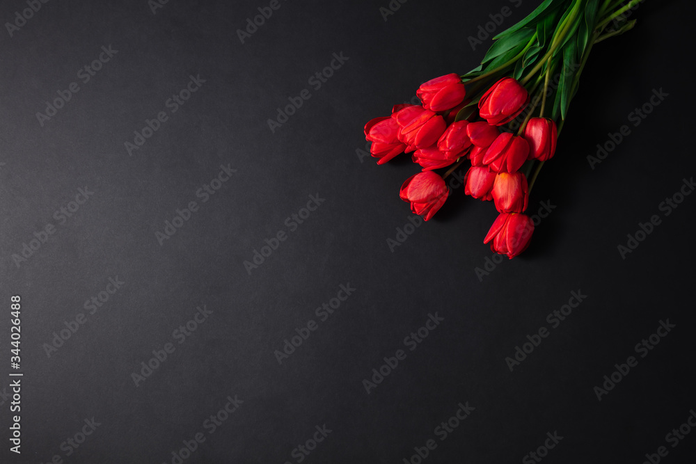 A bouquet of fresh red tulips on a black background. A large bouquet of fresh, spring flowers on a dark table. A bouquet of fresh red tulips on a black background. A large bouquet of fresh, spring flowers on a dark table.