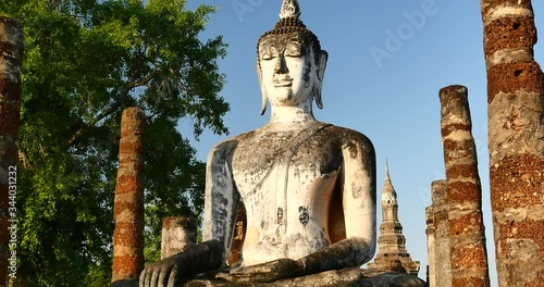 4k Mahathat temple in Sukhothai historical park; Thailand.Seated Buddha(Phra Atchana) at Wat Si Chum temple in Sukhothai Historical Park; a UNESCO world heritage site; Thailand.  photo