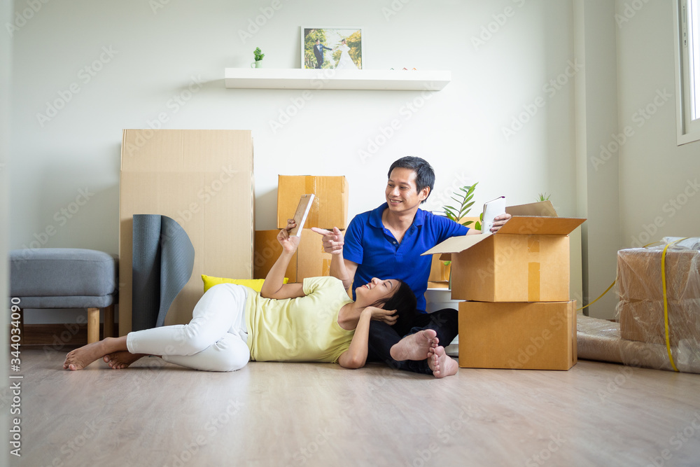 Couple sitting and resting after the tiredness of moving boxs into the house. Wife lying on lap of husband looking at photos and feeling happy. Move house, Moving out , Moving in ideas Couple sitting and resting after the tiredness of moving boxs into the house. Wife lying on lap of husband looking at photos and feeling happy. Move house, Moving out , Moving in ideas