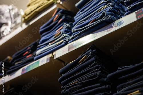 details of clothing and textile on display in clothing store folded, stacked and hanging