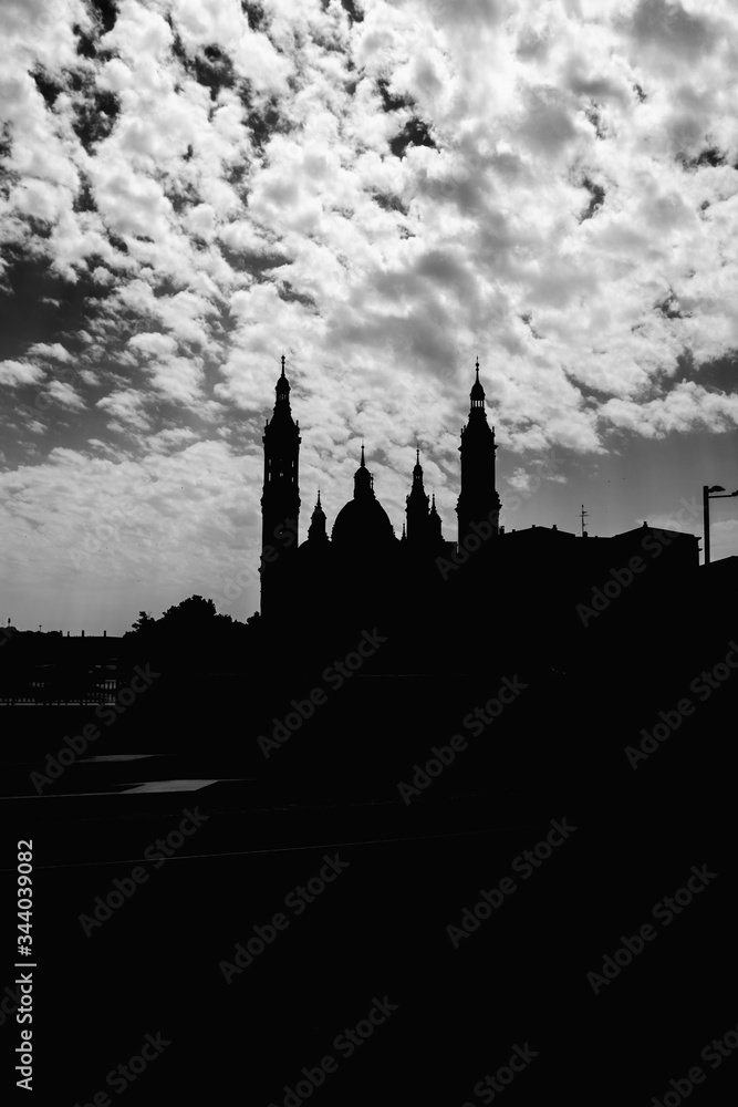 Silueta del Pilar, catedral de Zaragoza. Fotografia en blanco y negro con cielo soleado con nubes. 