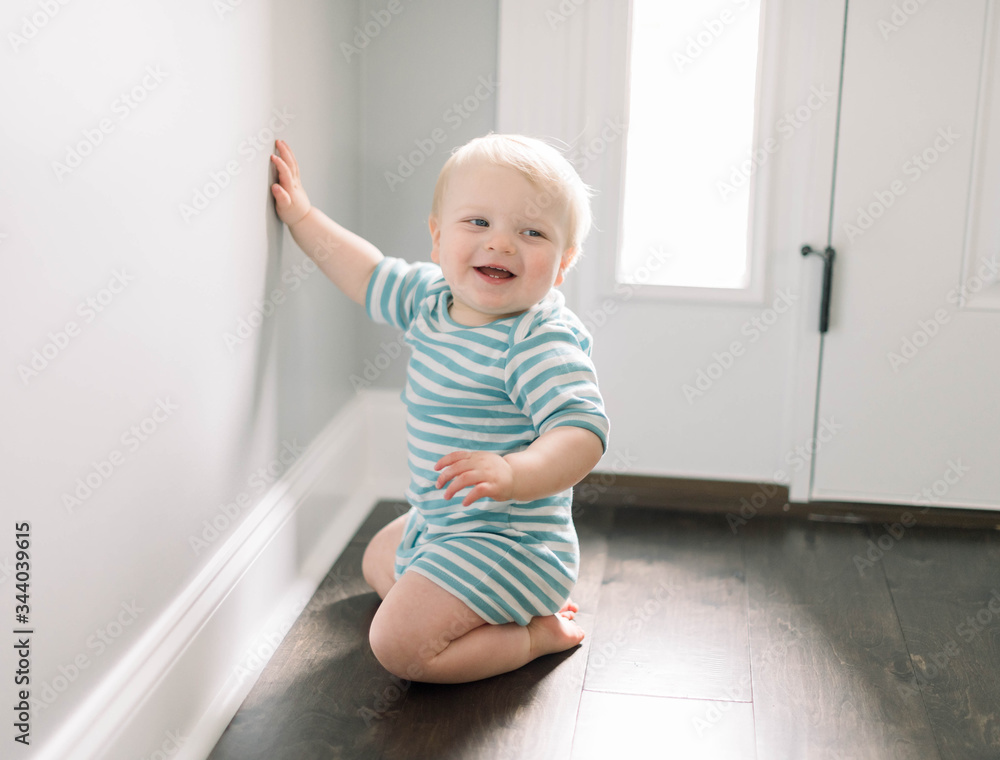 Toddler Baby Boy in Striped Romper Smiling, Laughing, and Looking Out of Window Toddler Baby Boy in Striped Romper Smiling, Laughing, and Looking Out of Window
