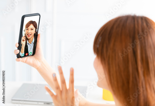 young woman working at home and using mobile phone with video chat