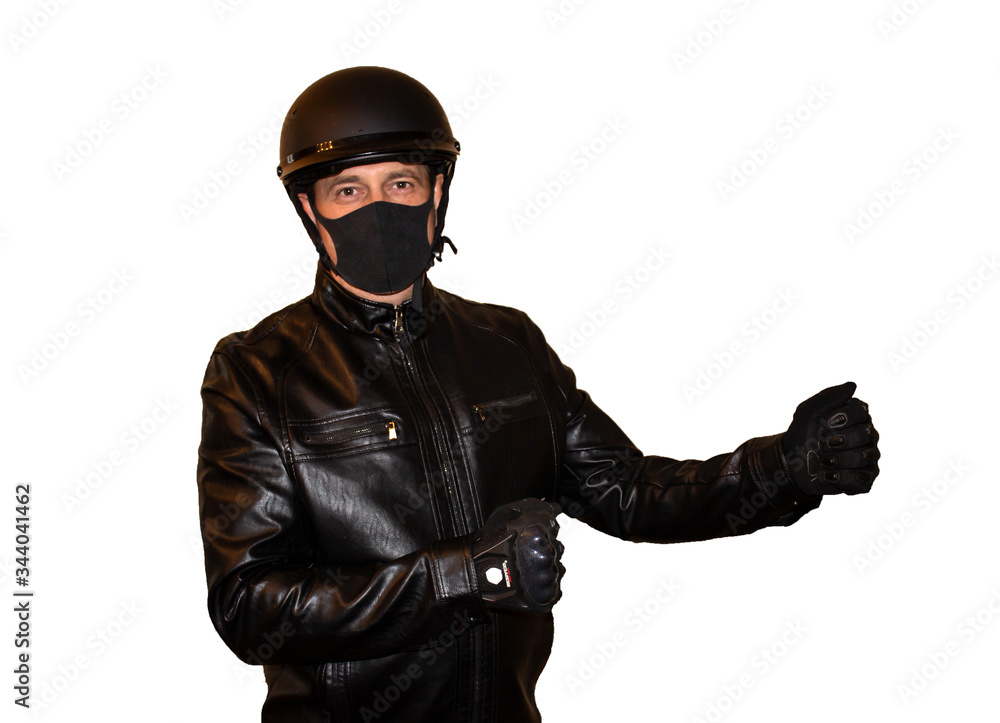 Isolated on white background man motorcyclist in a helmet and a mask that protects against coronavirus. Black jacket, protection and biker gloves Isolated on white background man motorcyclist in a helmet and a mask that protects against coronavirus. Black jacket, protection and biker gloves