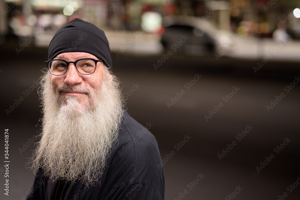 Face of happy mature bearded hipster man thinking in the city streets Face of happy mature bearded hipster man thinking in the city streets