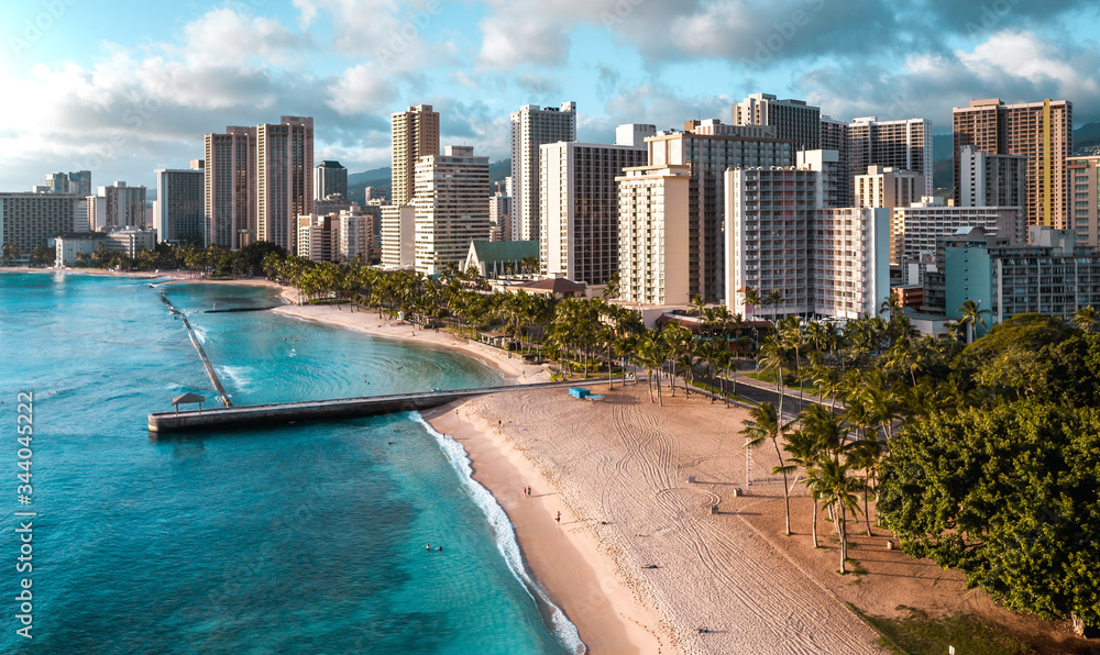 Top view of empty Waikiki beach in Hawaii, hotels and beautiful sand shore with turquoise ocean water and reefs, aerial drone shot