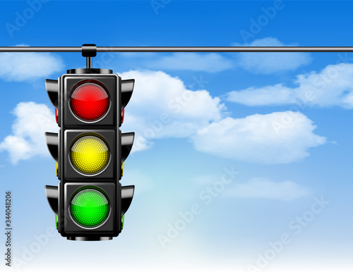 Traffic lights with all three colors on hanging against blue sky