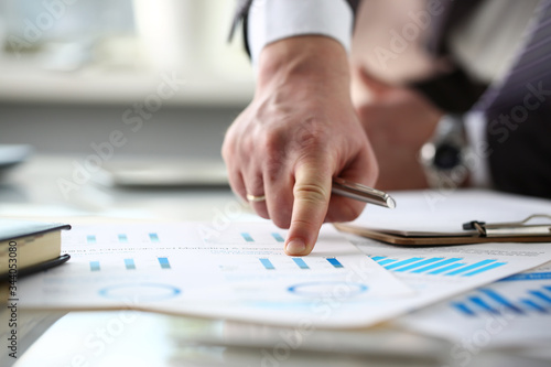 Male arm point finger at important paper on table in office closeup. Paperwork job trade balance bank credit loan money invest payment irs commerce partnership man in suit concept