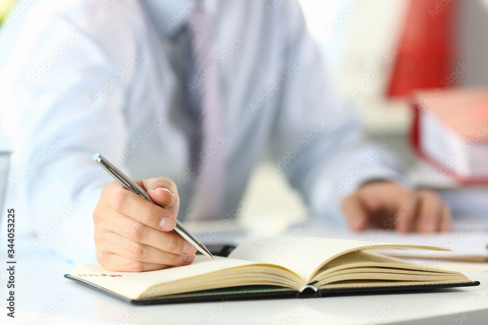 Male arm in suit and tie hold silver pen filling schedule in notepad at office workplace closeup. Legal law consult assistance gesture or finance investment advisor clerk job information gesture Male arm in suit and tie hold silver pen filling schedule in notepad at office workplace closeup. Legal law consult assistance gesture or finance investment advisor clerk job information gesture