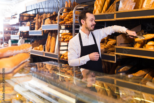 Male shop assistant demonstrating delicious loaves of bread in bakery
