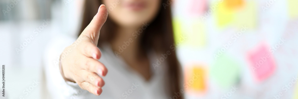 Cheerful female clerk welcoming business partner by shaking hand as sign of future achievements and prospects closeup - obrazy, fototapety, plakaty 