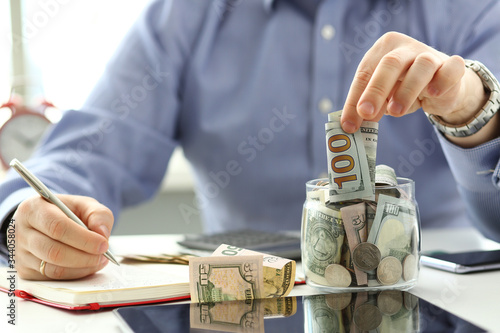 Male hand depositing some extra money in future needs closeup