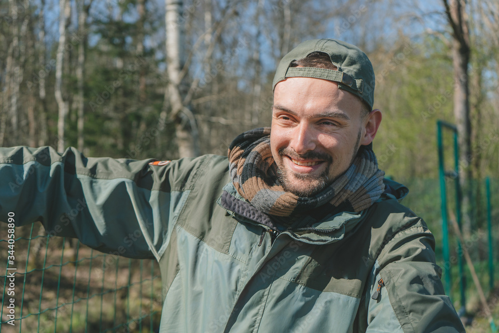 Obraz premium Smiling handsome gardener working in backyard. Portrait of man landscaping and taking care of his yard on a sunny day. 