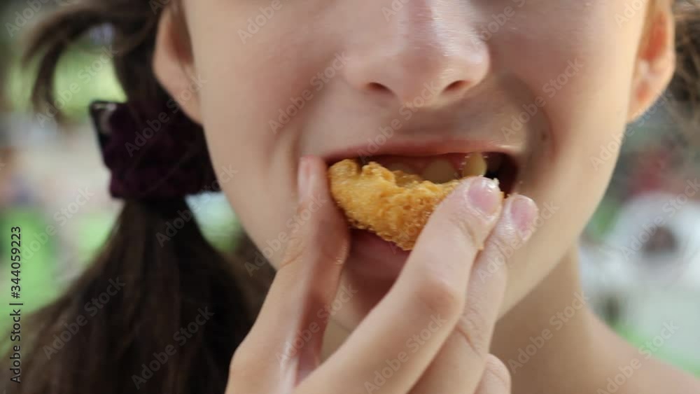 A teenage girl eats nuggets. Fast food on the street. A teenage girl eats nuggets. Fast food on the street.