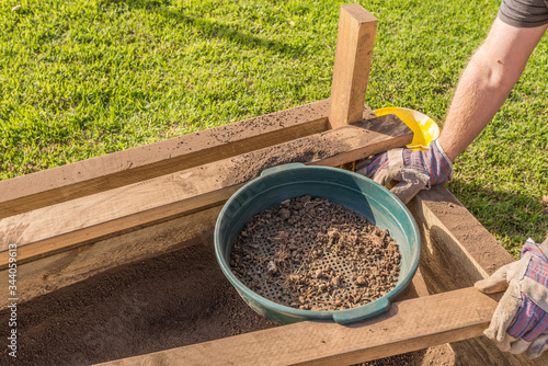 Fotografija Sifting soil through a garden sieve to remove rubbish