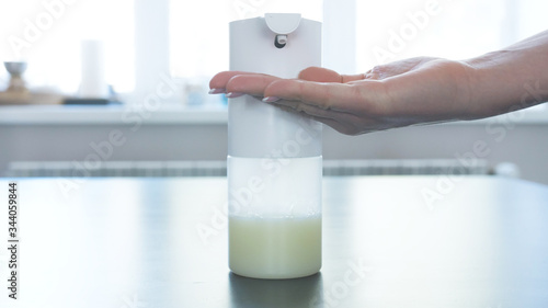 Girl and man using automatic foam soap dispenser, washing hands, close, macro, on the windowsill