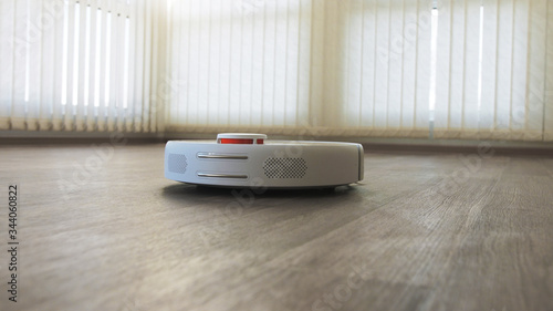 White robotic vacuum cleaner on linoleum wood floor smart cleaning technology