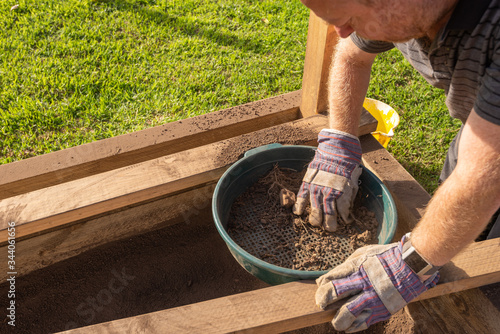 Bilde på lerret Sifting soil through a garden sieve to remove rubbish