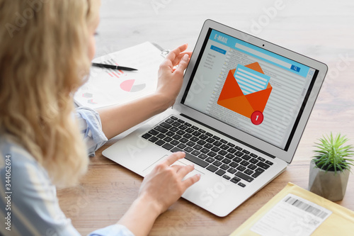 Young woman with laptop checking her e-mail at home