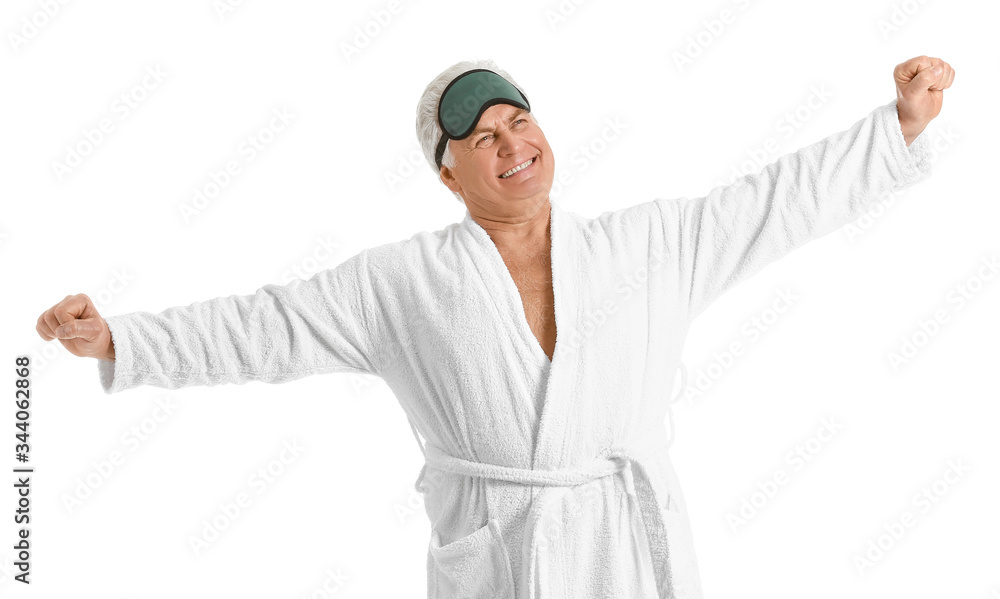 Happy mature man in bathrobe and with sleep mask on white background