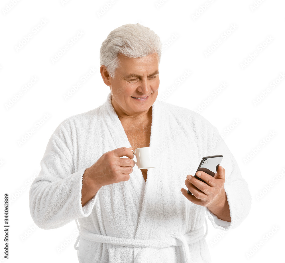 Mature man in bathrobe, with mobile phone and cup of coffee on white background Mature man in bathrobe, with mobile phone and cup of coffee on white background