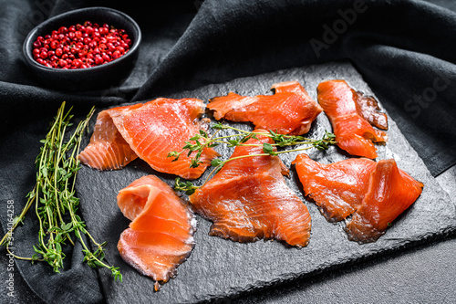 Smoked salmon slices with spices and herbs. Organic fish. Black background. Top view