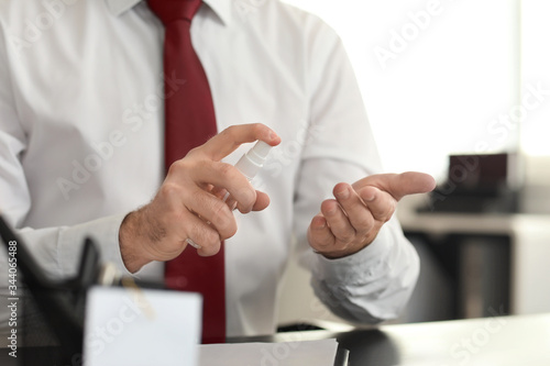 Businessman with disinfectant in office, closeup
